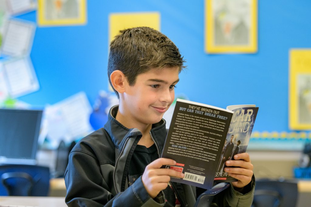 Boy reading a book in a classroom at The College School